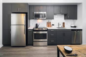 A kitchen with stainless steel appliances and black cabinets 